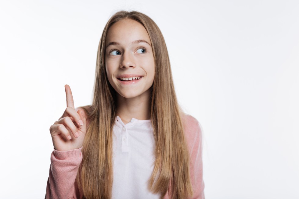 Smiling teenage girl pointing up with her finger